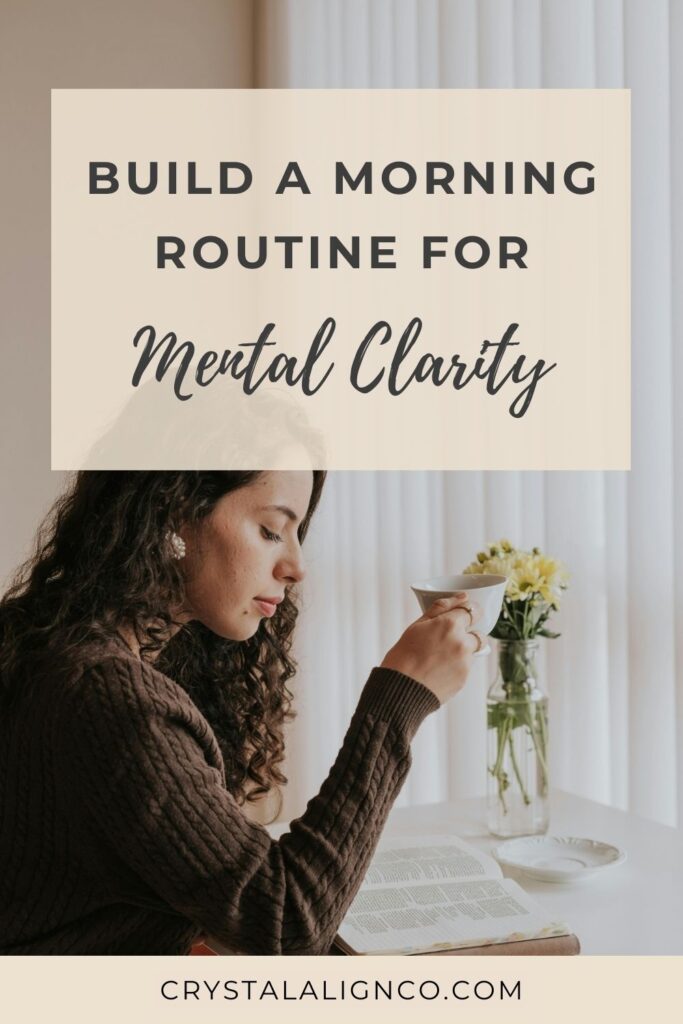 Woman in a brown sweater sits quietly at a table with a cup of tea and an open book, creating a calm and cozy morning routine atmosphere. A vase of yellow flowers adds a peaceful touch, reflecting a gentle start to the day focused on mental clarity