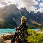 Woman Sitting on a beach looking out at the river and mountains