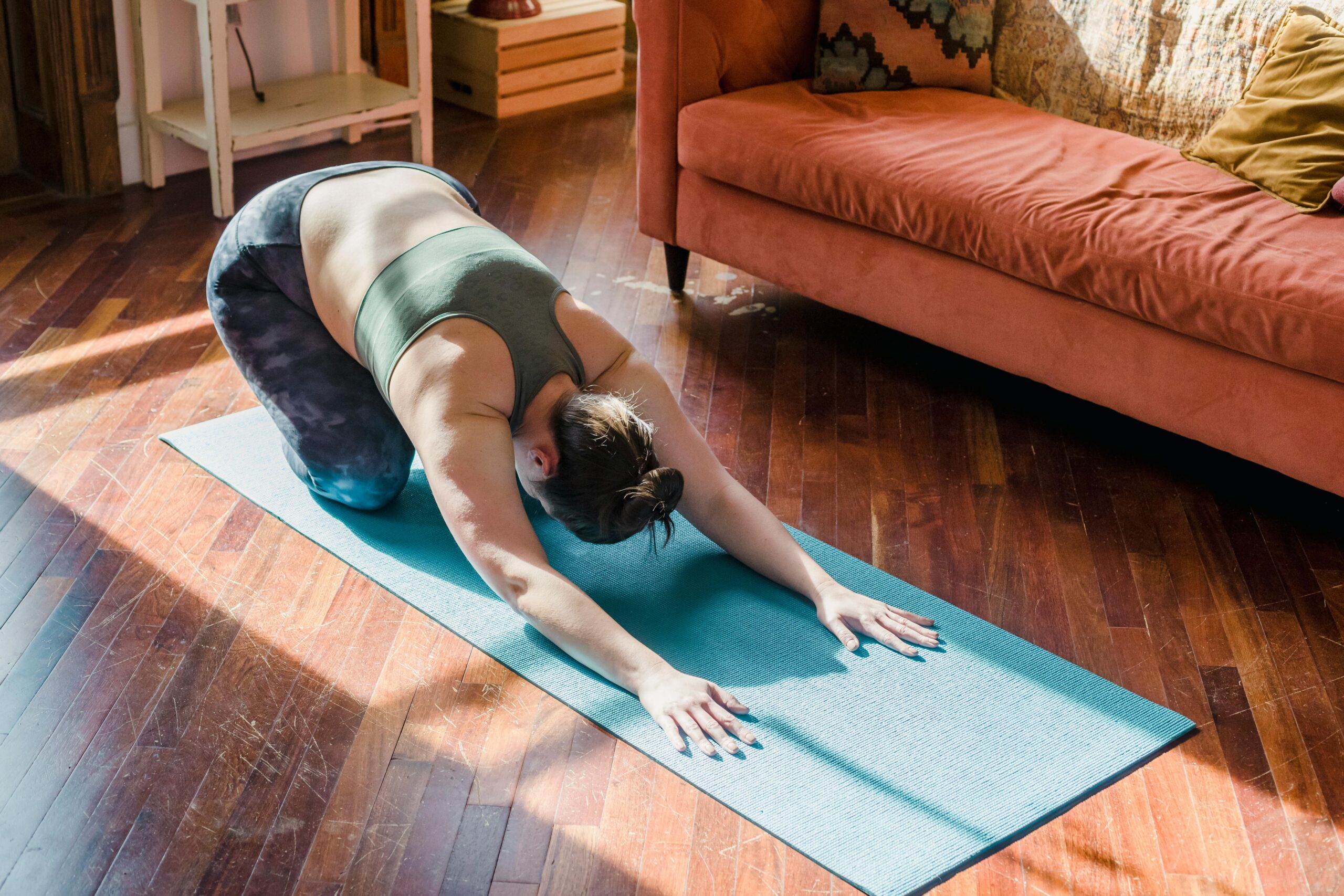 woman doing yoga in her livingroom with sun streaming through the windows