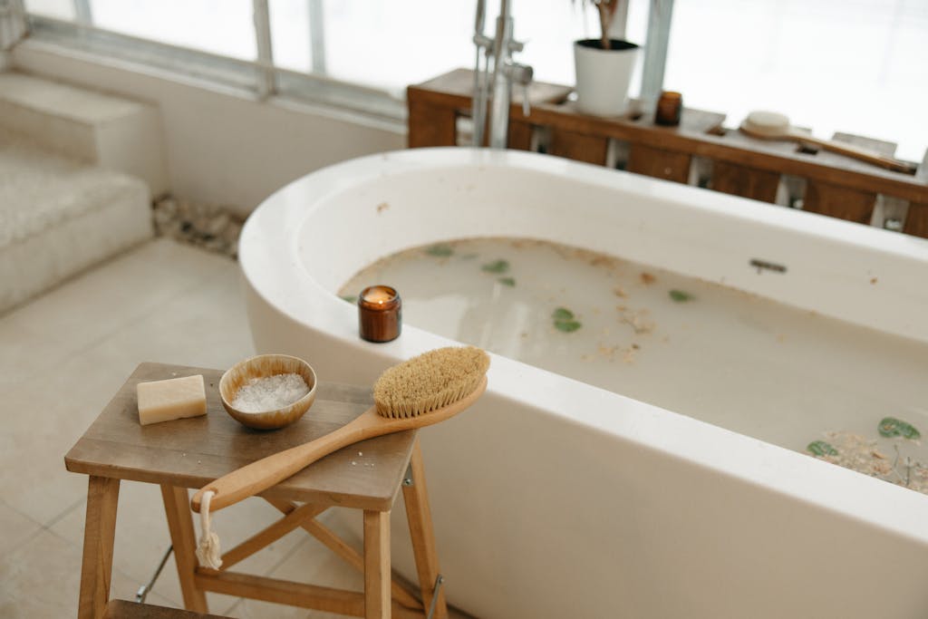 Relaxing spa bath setup with luxurious essentials including soap, brush, salts, and candle.
