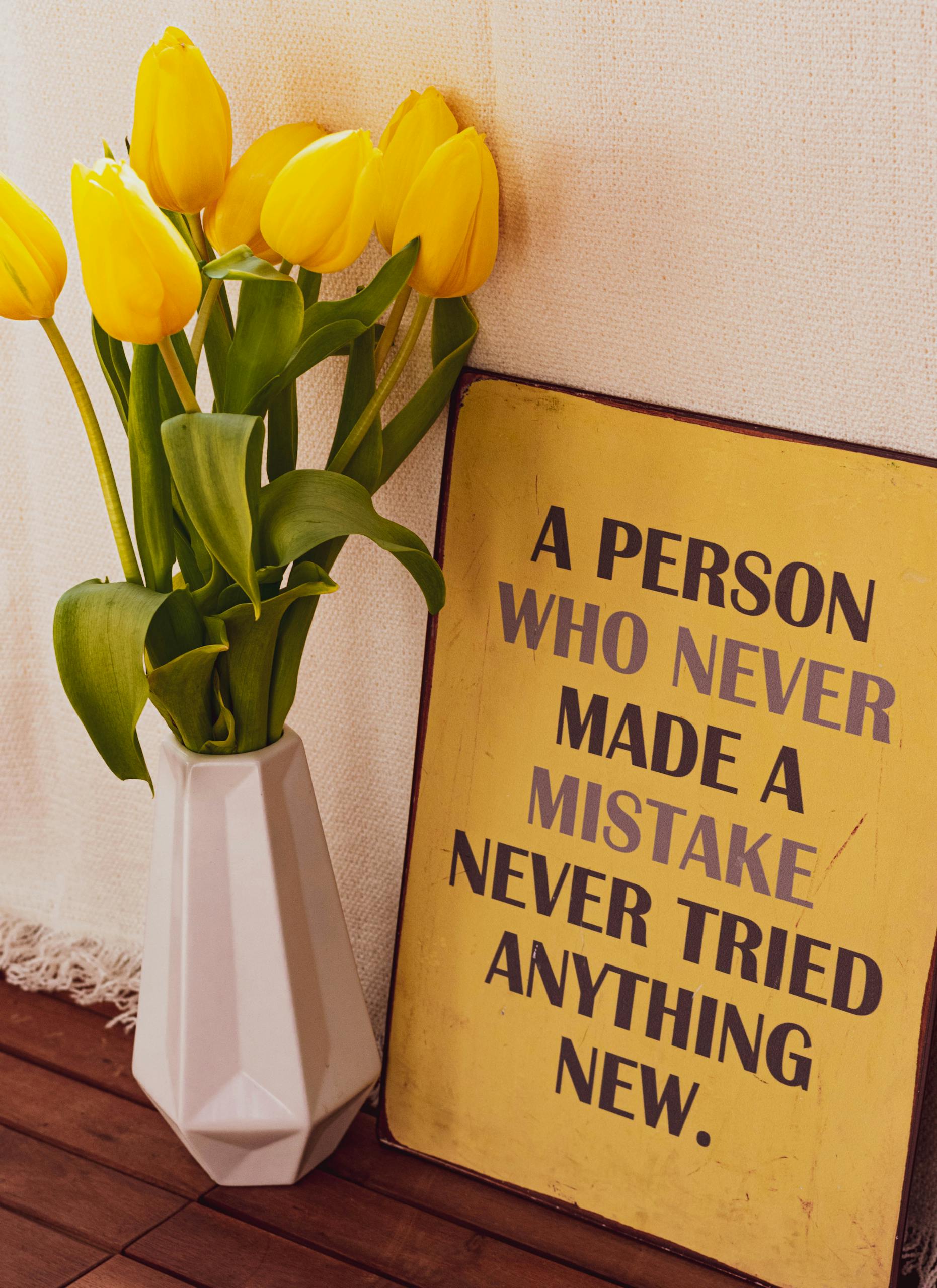 Yellow tulips displayed beside a motivational quote poster in an indoor setting.