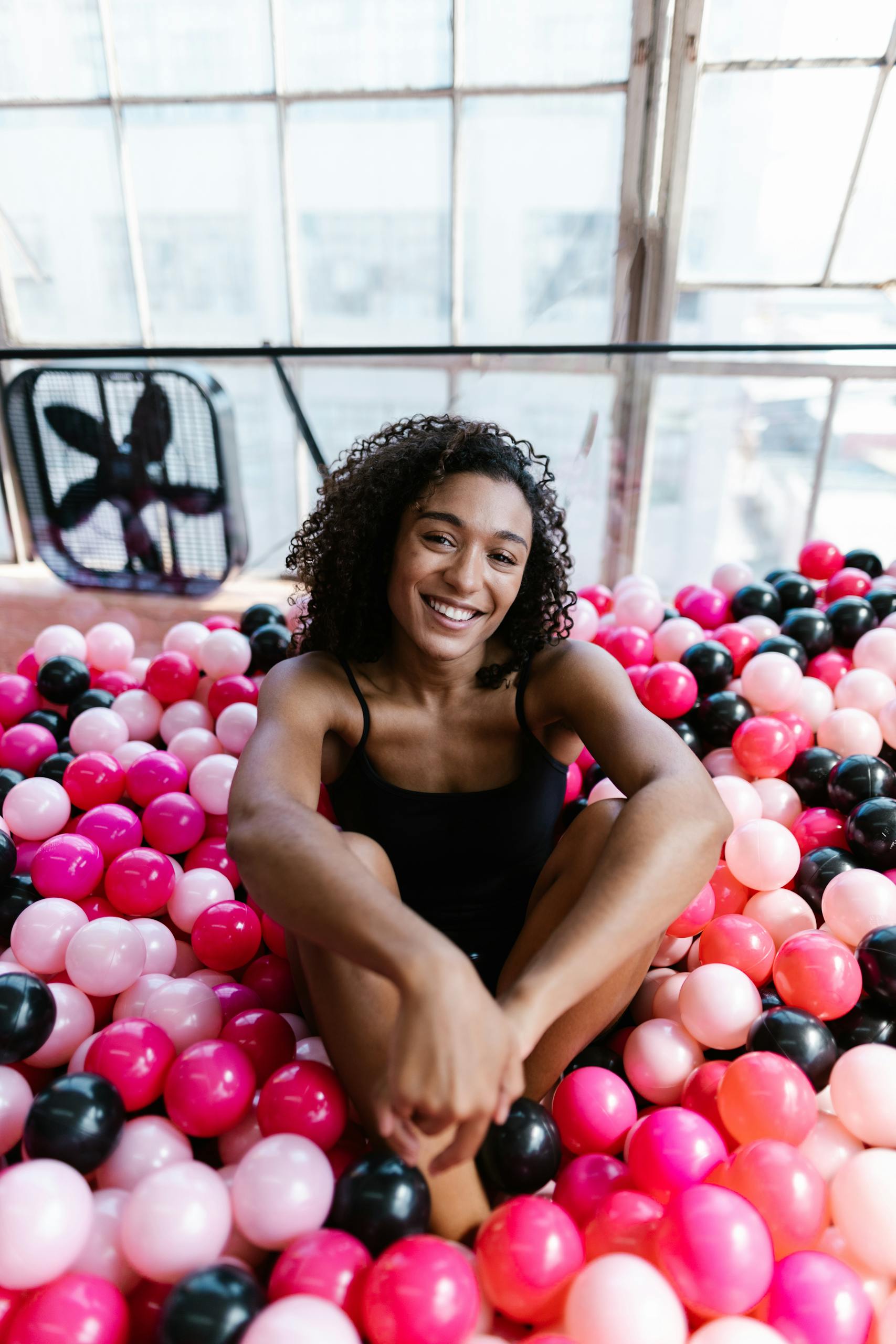 A happy woman enjoying colorful plastic balls indoors, capturing a joyful moment.