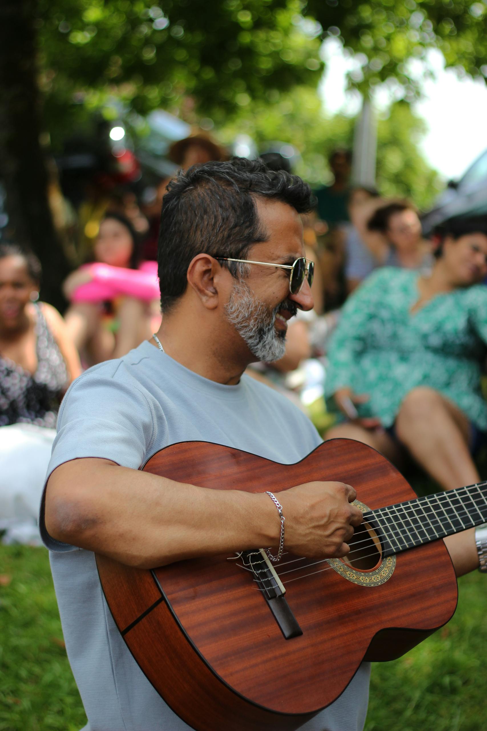 A man joyfully playing an acoustic guitar in a park setting, Braga, Portugal.