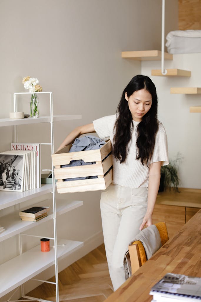 Asian woman organizing laundry in a modern home interior, emphasizing cleanliness and minimalism. January reset