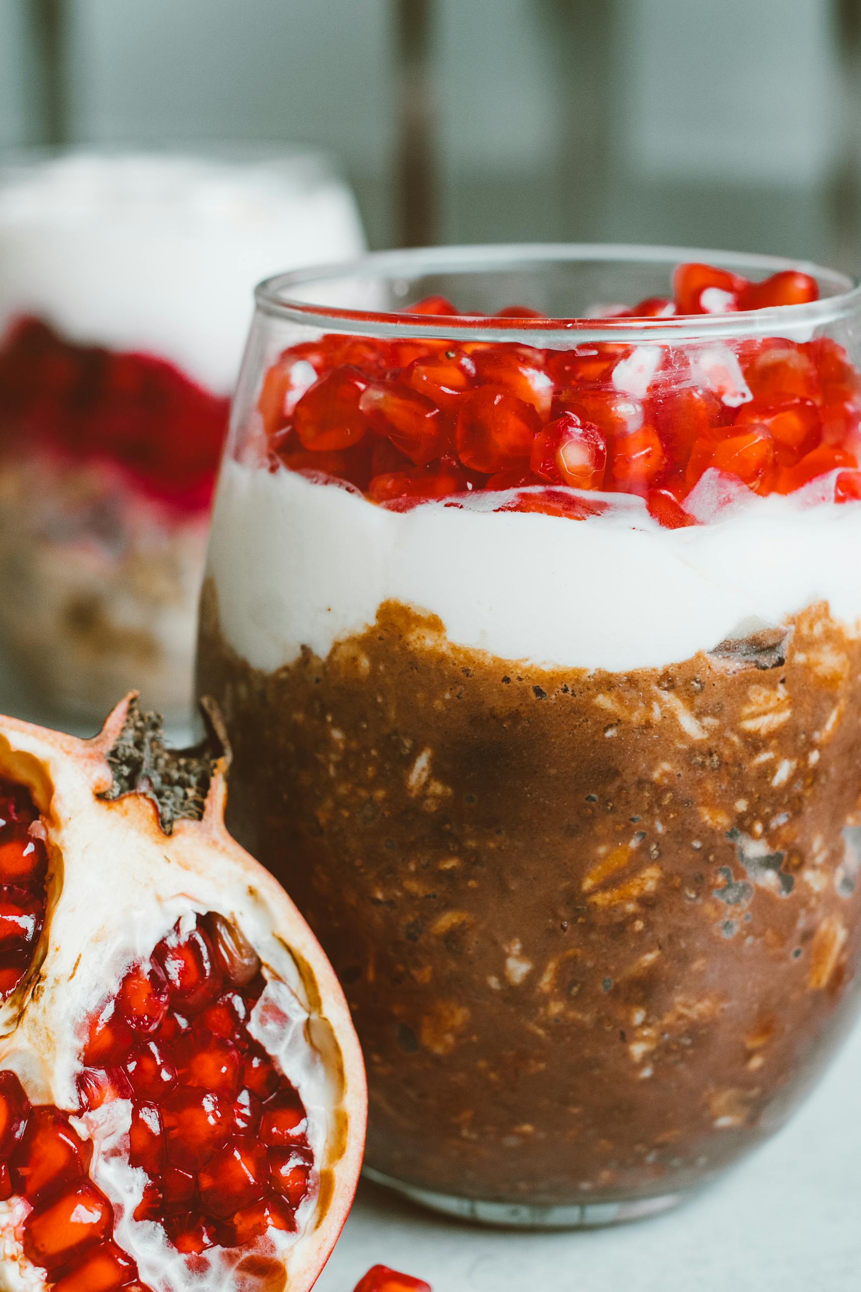 Close-up of a chocolate and pomegranate parfait with layers of cream and fruit in a glass.