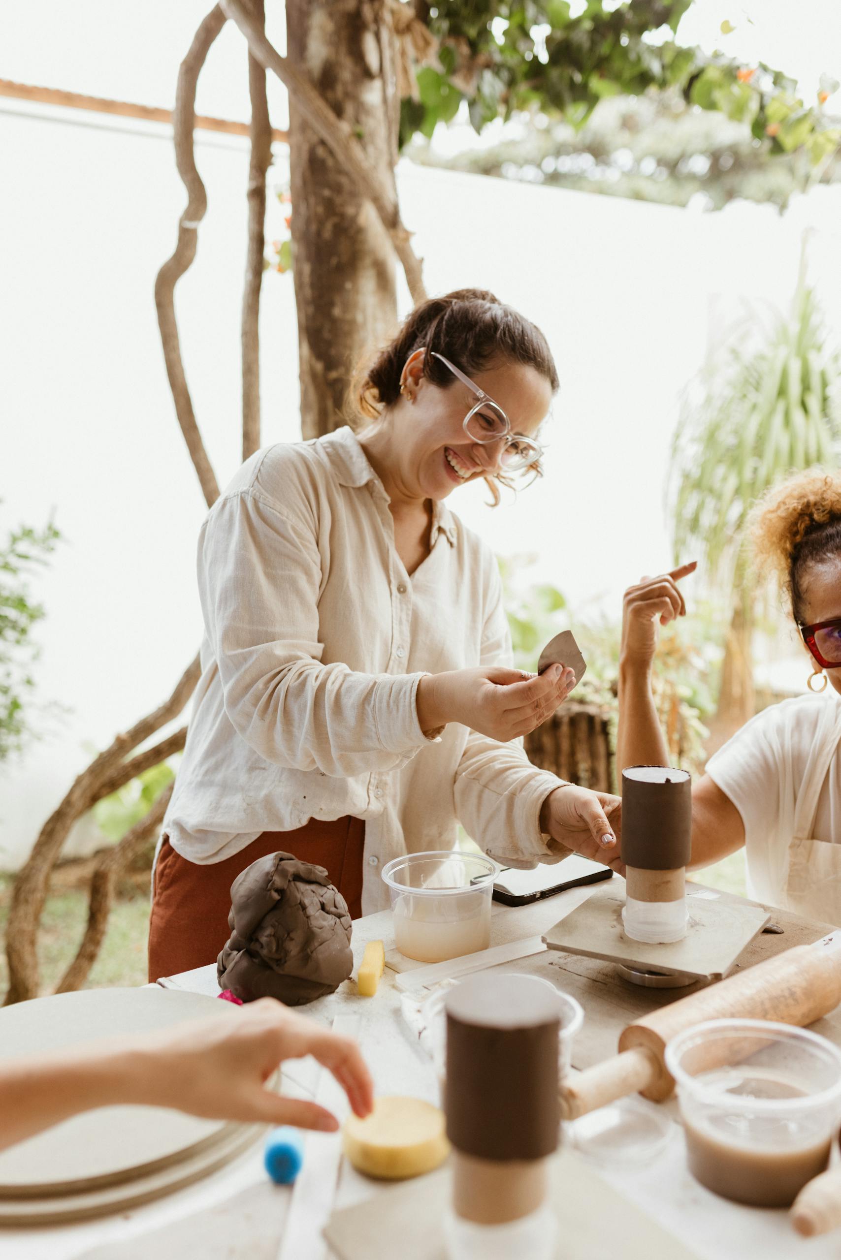 Happy friends enjoying a pottery class outdoors, fostering creativity and togetherness.