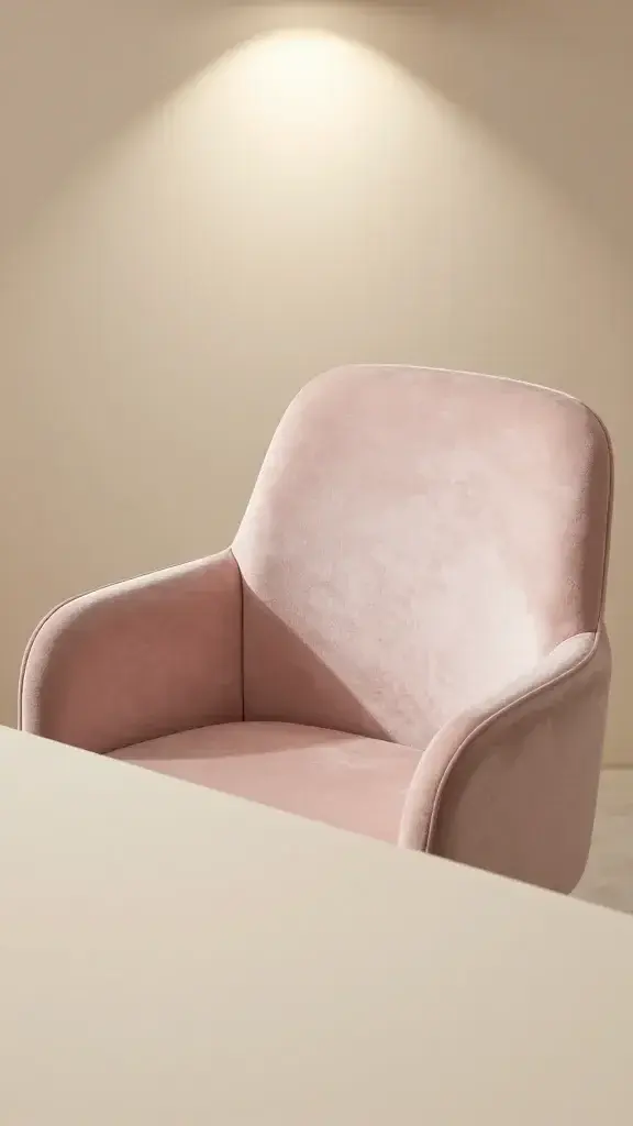 closeup of blush velvet desk chair spotlighted on soft beige desk