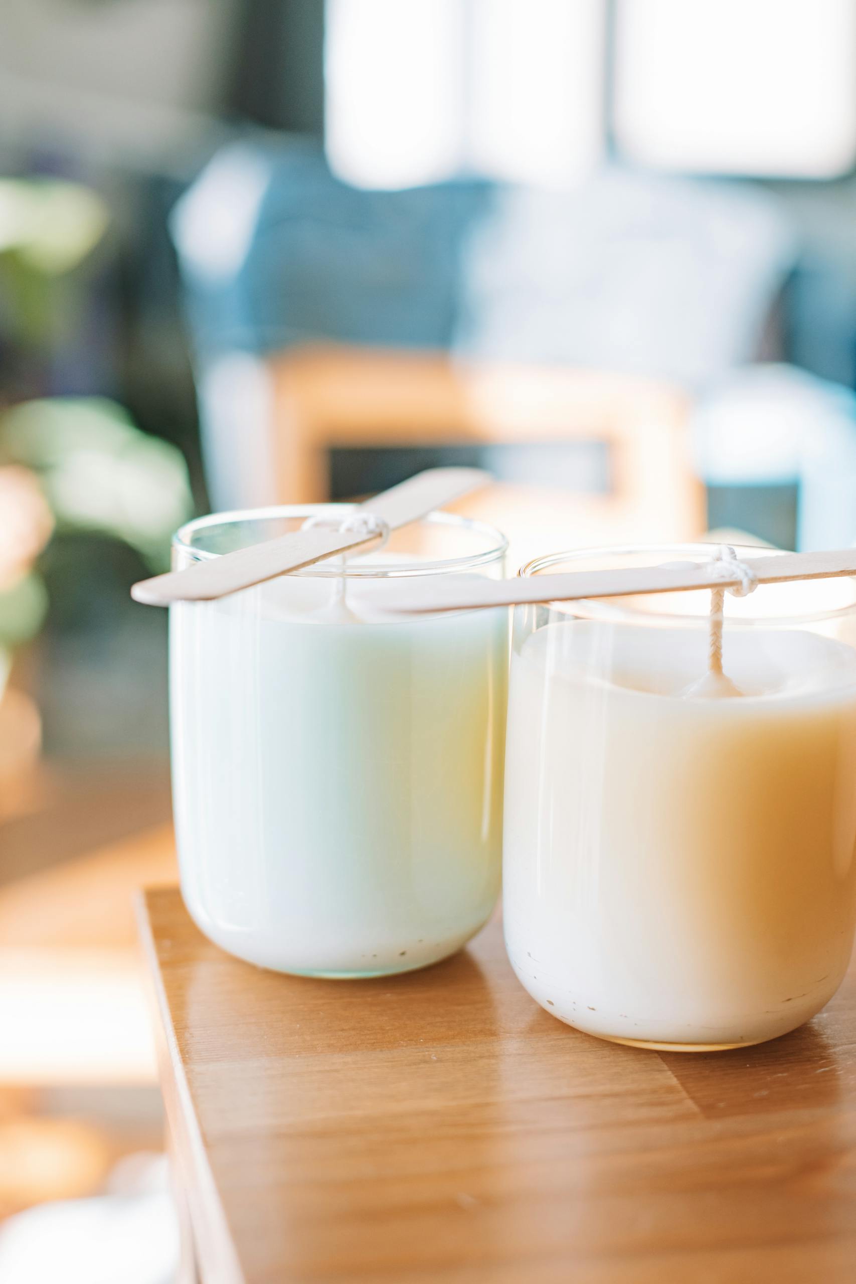 Two homemade candles with popsicle stick supports, captured in warm natural light.
