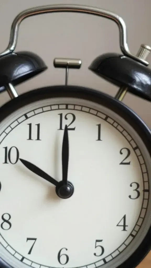 Closeup of a solitary alarm clock with a blurred snooze button backdrop