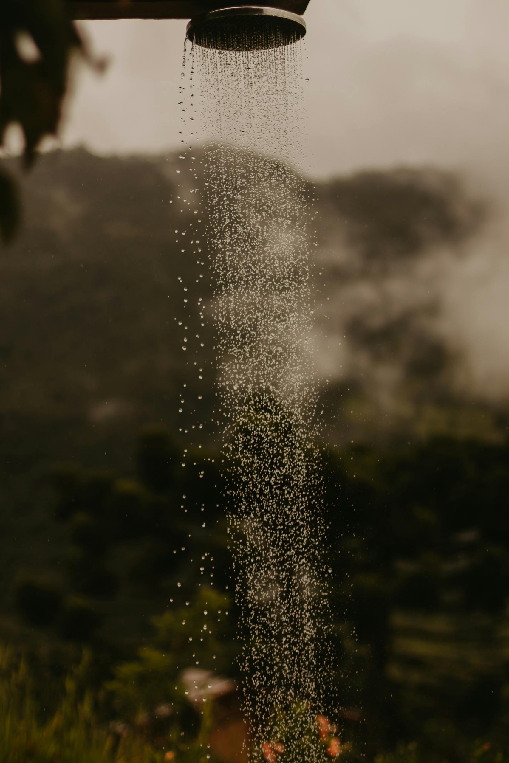 Outdoor shower in a natural setting with water droplets cascading down. Perfect for travel or lifestyle themes.