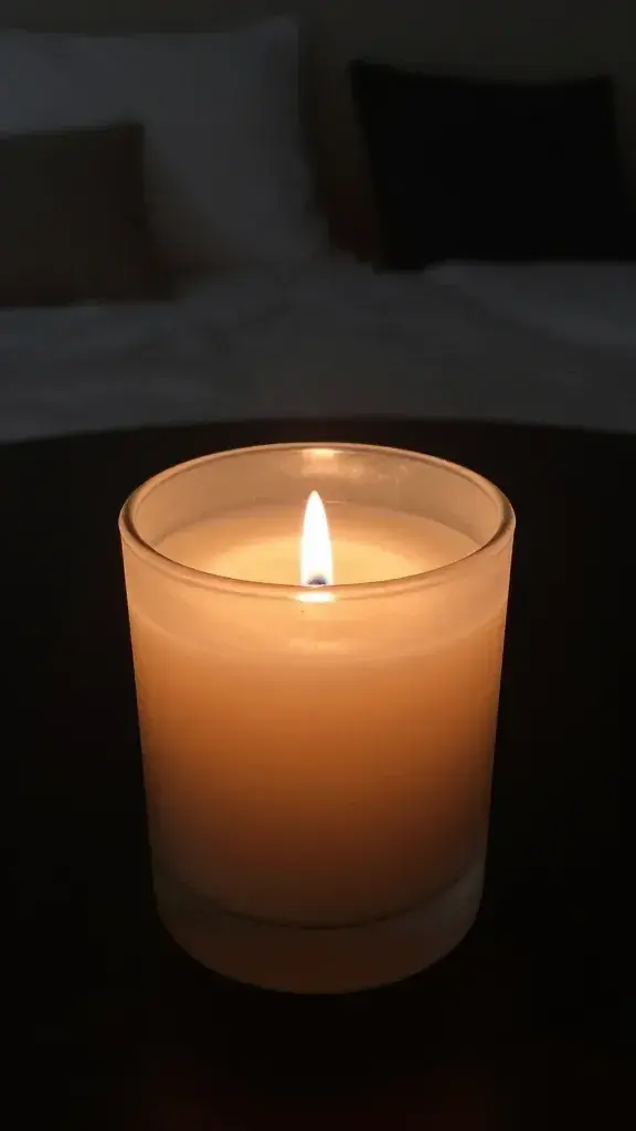 closeup of a lit fall-scented candle in a dimly lit bedroom