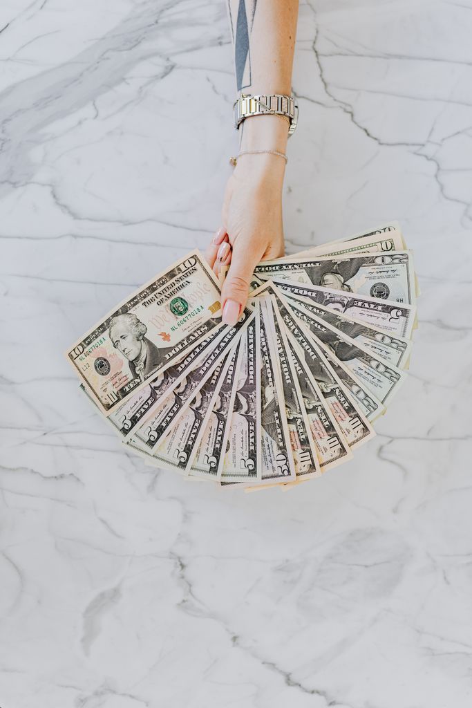 woman holding a fan of us dollar bills how to manifest money
