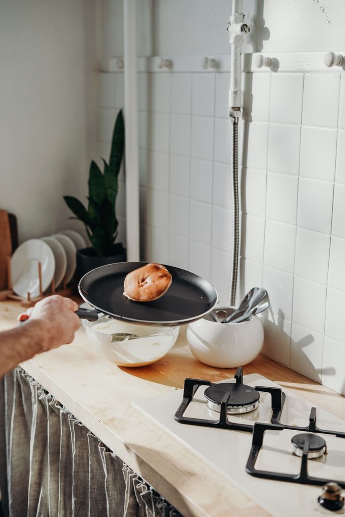 A person cooking pancakes on a stove in a bright kitchen, capturing a homey morning vibe.Sunday routine for a productive week