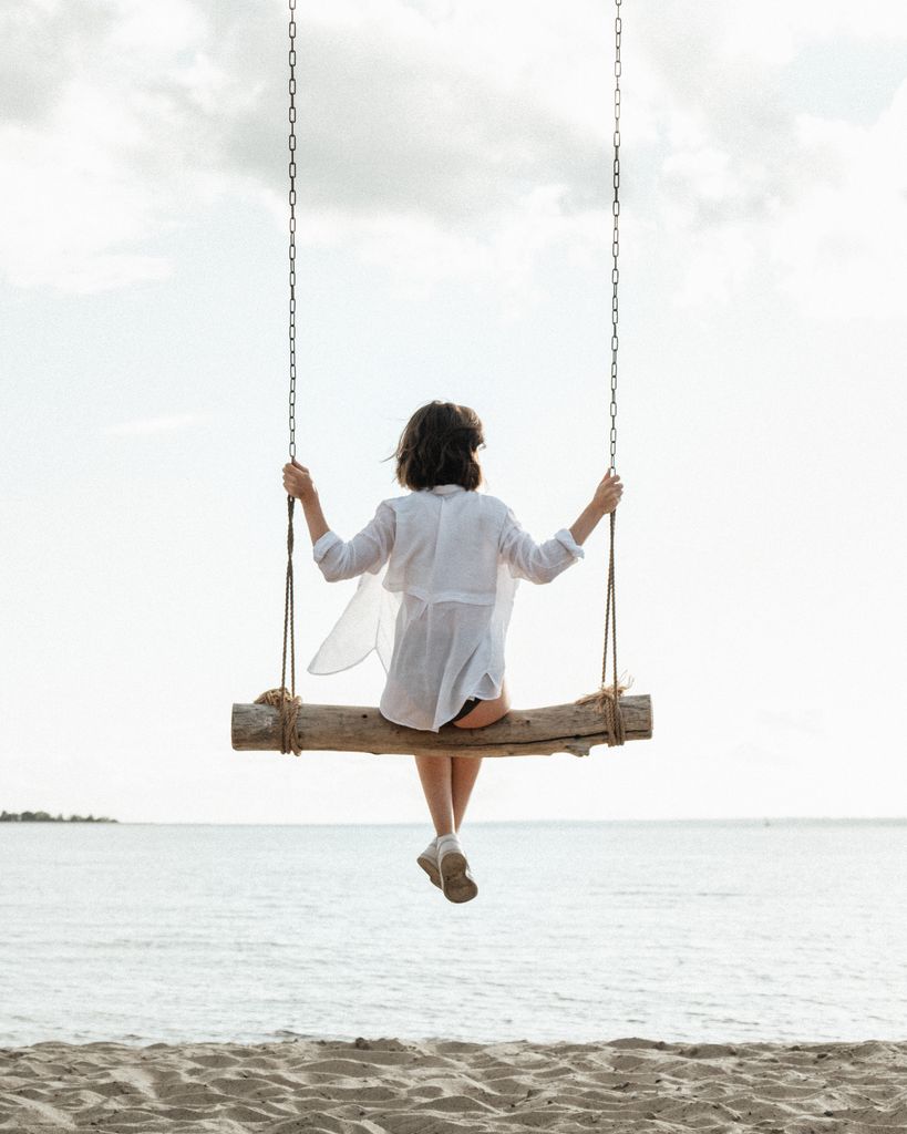 A person enjoys a calming swing by the shoreline, embracing tranquility.