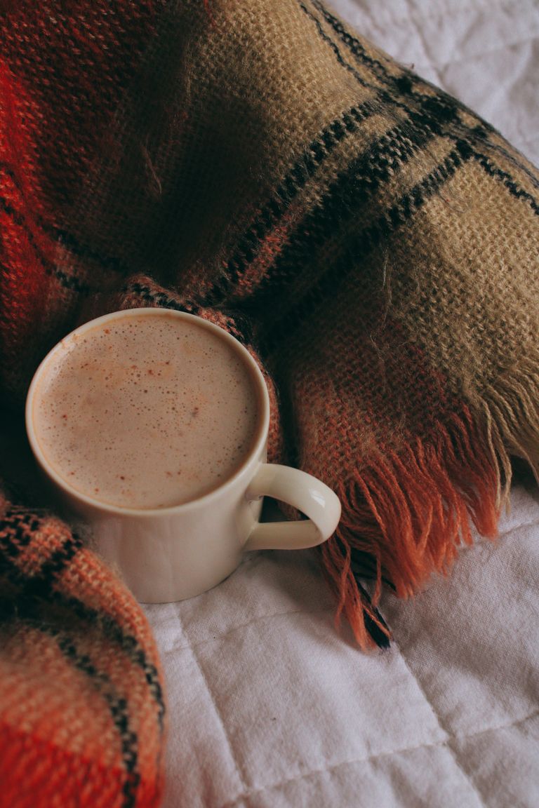 A warm cup of coffee nestled on a plaid blanket, evoking a cozy winter atmosphere.