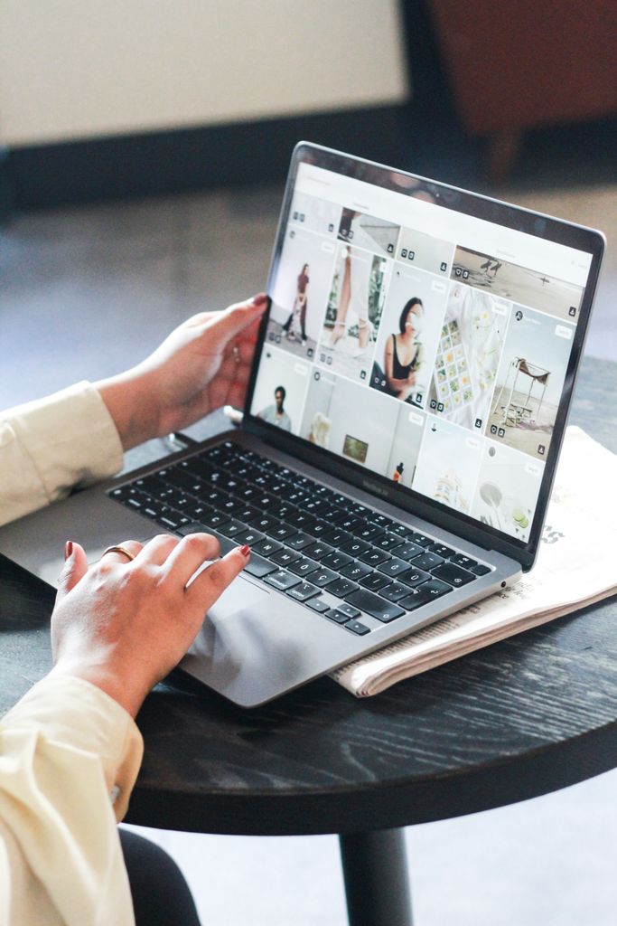 A woman browses a fashion blog on her laptop while working indoors, focused on the screen digital vision board ideas