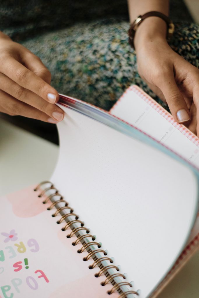 A woman flipping through colorful pages of a planner, focused and thoughtful.