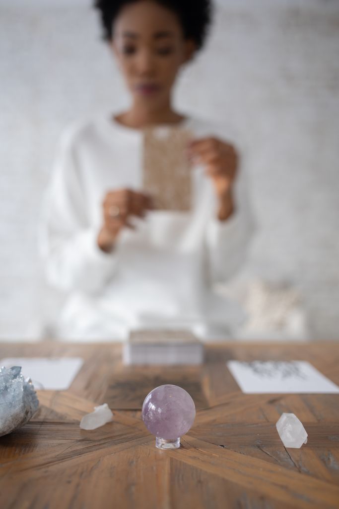 Amethyst crystal sphere with an out-of-focus woman holding a card in the background.