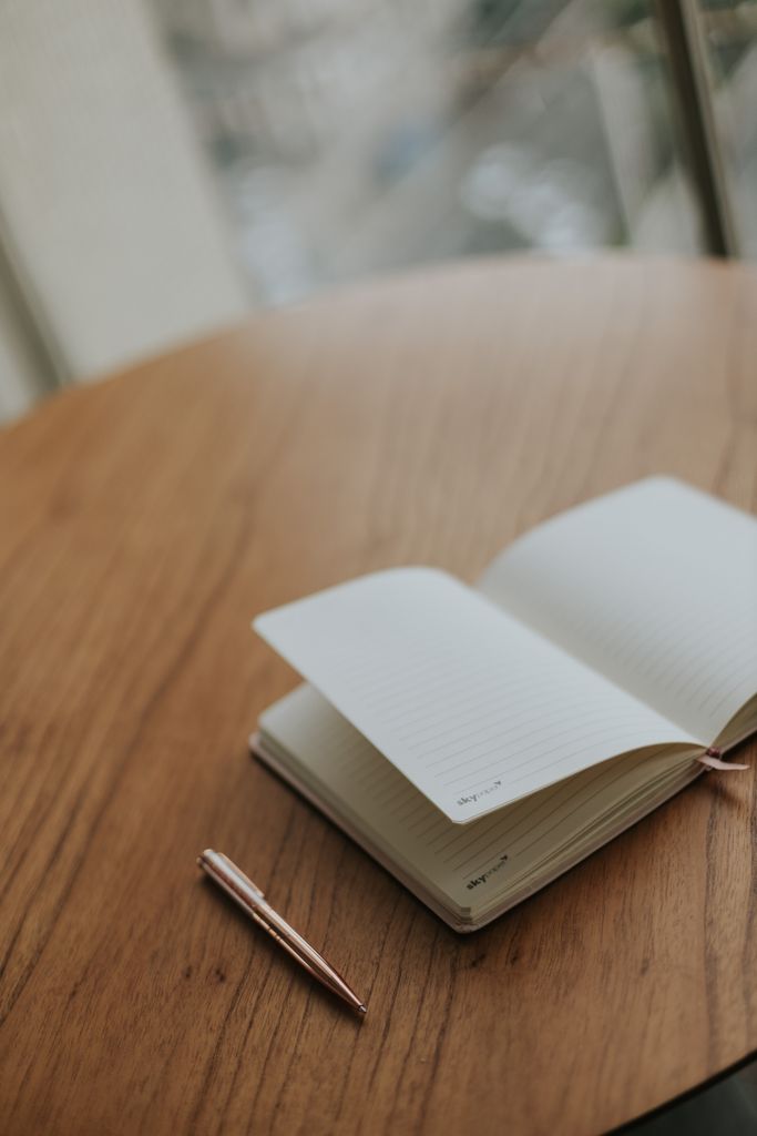 An open notebook and pen on a wooden table, perfect for creativity and journaling.