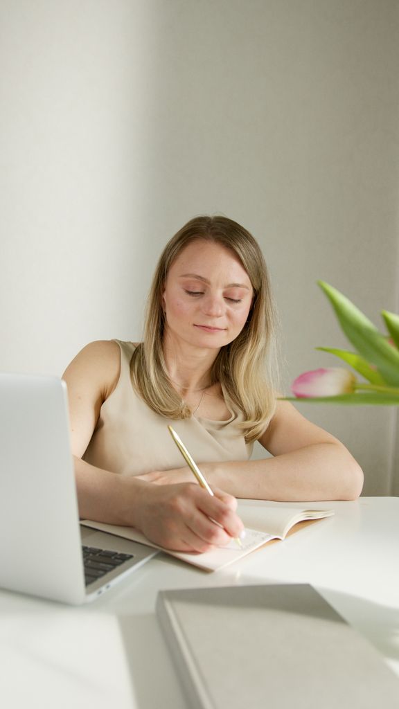Businesswoman working with laptop and notebook at a bright desk.how to write affirmations