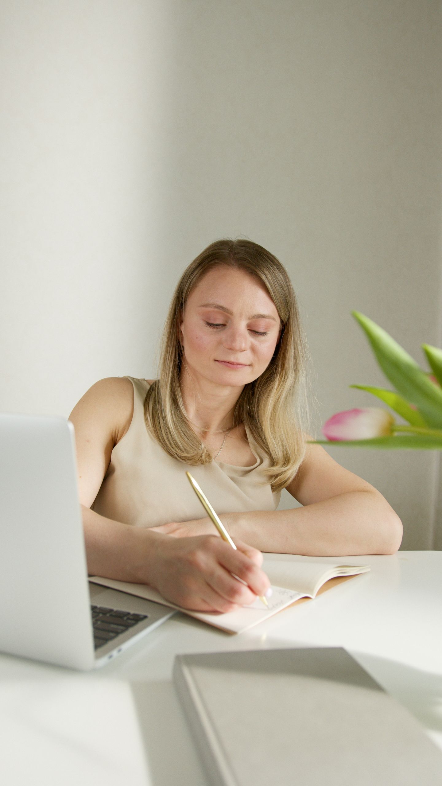 Businesswoman working with laptop and notebook at a bright desk.