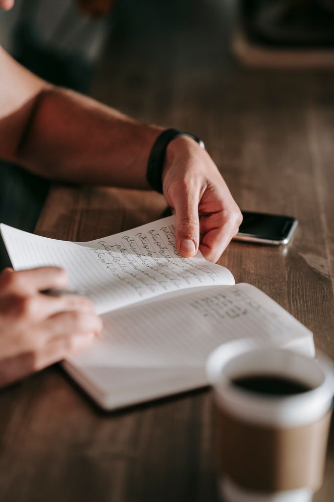 Close-up of a person journaling indoors with coffee, showcasing selective focus and depth of field. 30 day journal challenge