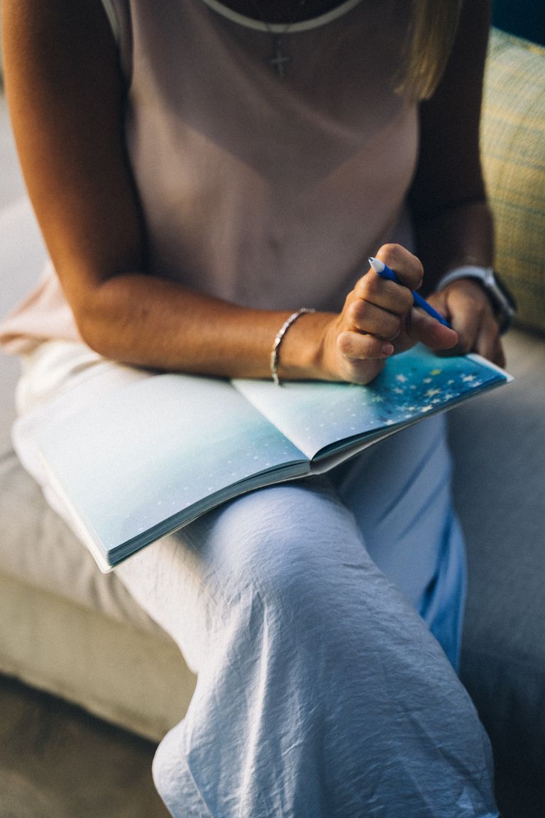 Close-up of a woman gratitude journal prompts sitting with a journal and pen, focusing on reflection and creativity.