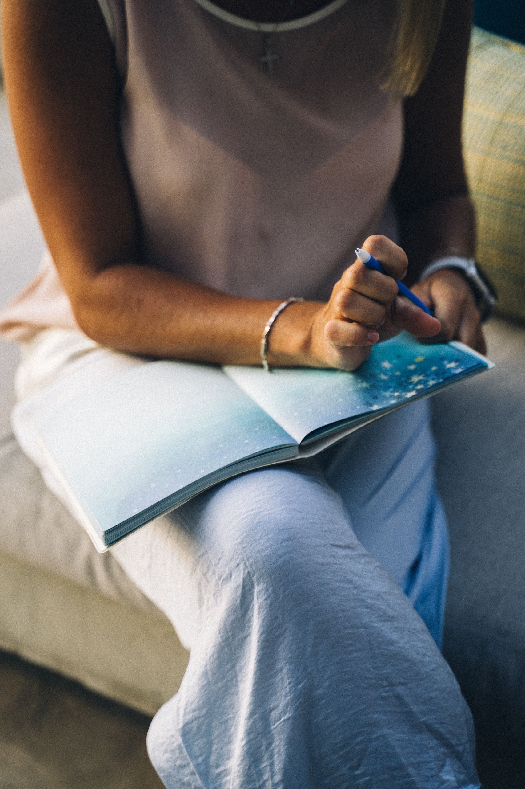 Close-up of a woman gratitude journal prompts sitting with a journal and pen, focusing on reflection and creativity.