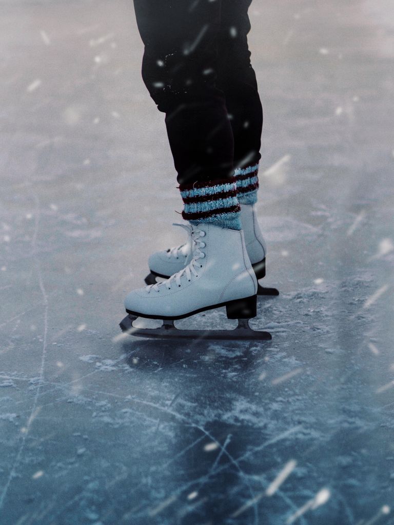 Close-up of person ice skating outdoors, showcasing ice skates in winter setting.January bucket list ideas