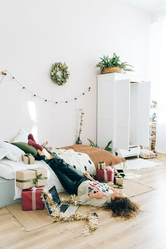 Cozy room with a woman relaxing amidst Christmas decorations and gifts ready for a Christmas night routine