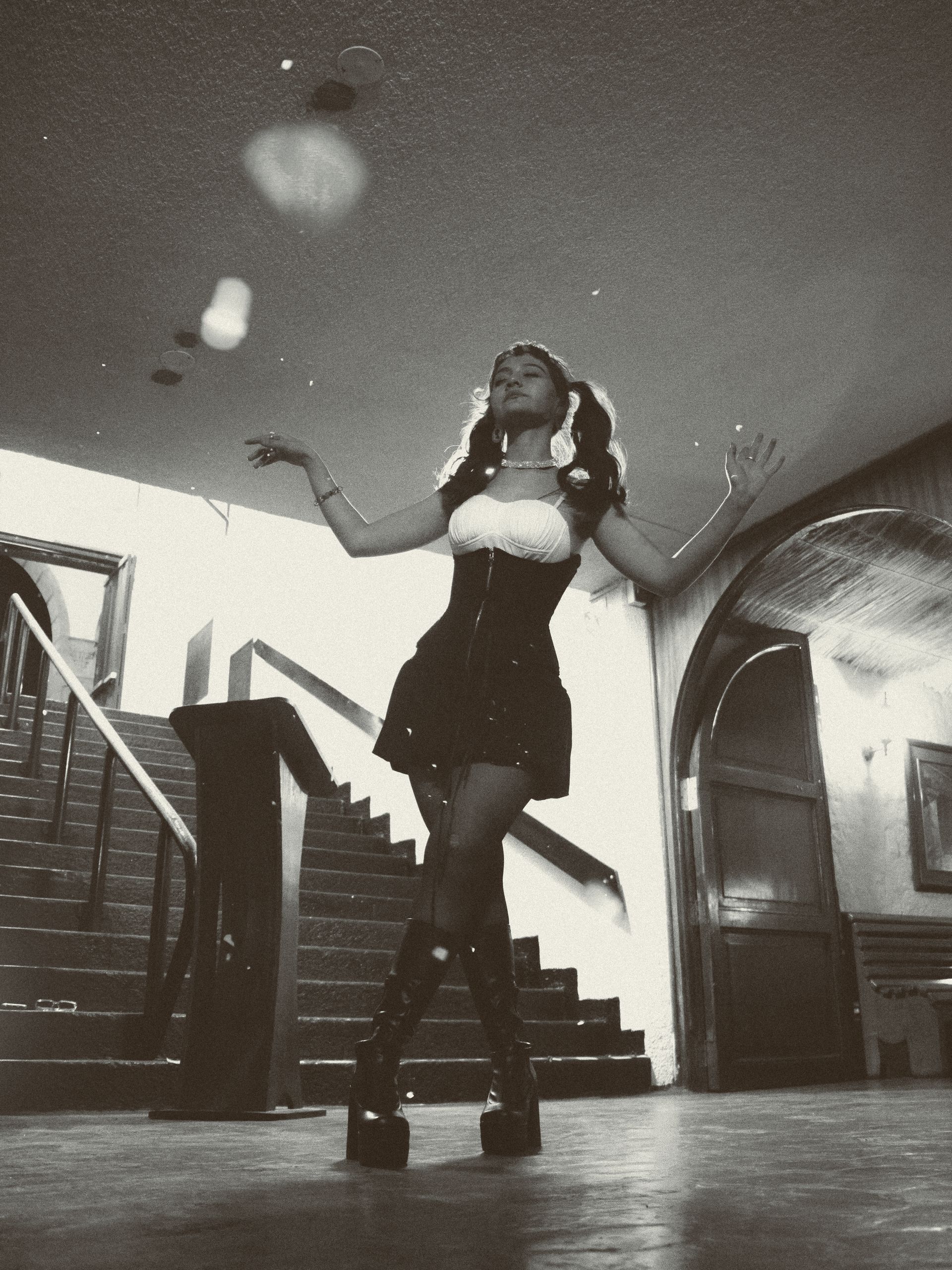 Elegant black and white portrait of a woman dancing indoors with a vintage flair.