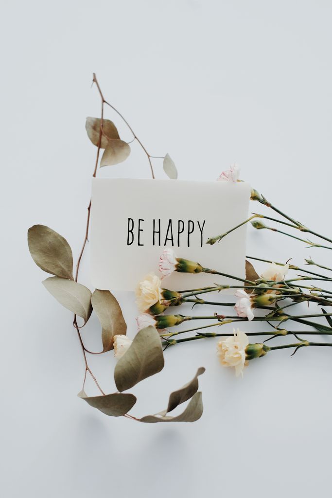 Elegant card with 'Be Happy' text surrounded by dried leaves and white flowers.