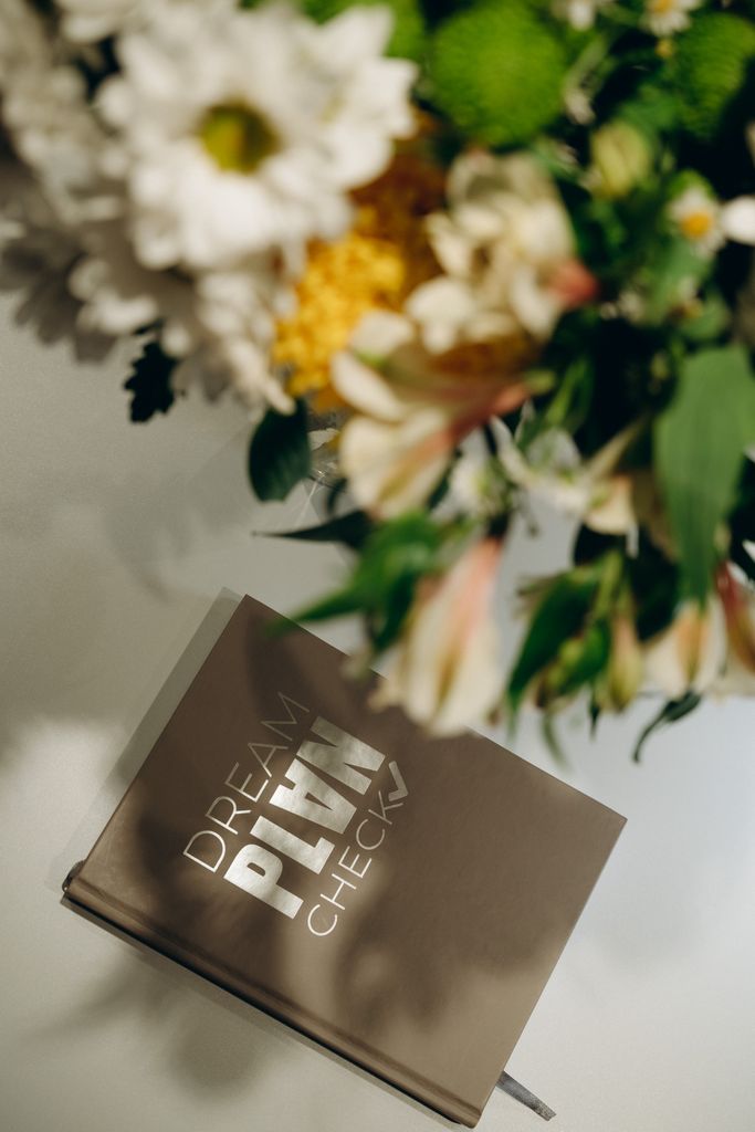 Elegant floral bouquet beside a 'Dream Plan Check' planner, ideal for creative planning.