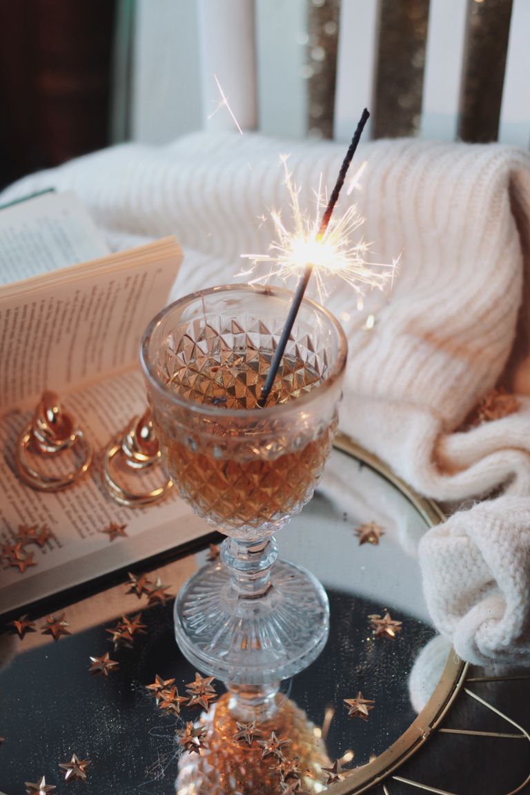 Elegant glass with drink and sparkler on a reflective surface, creating a festive vibe.