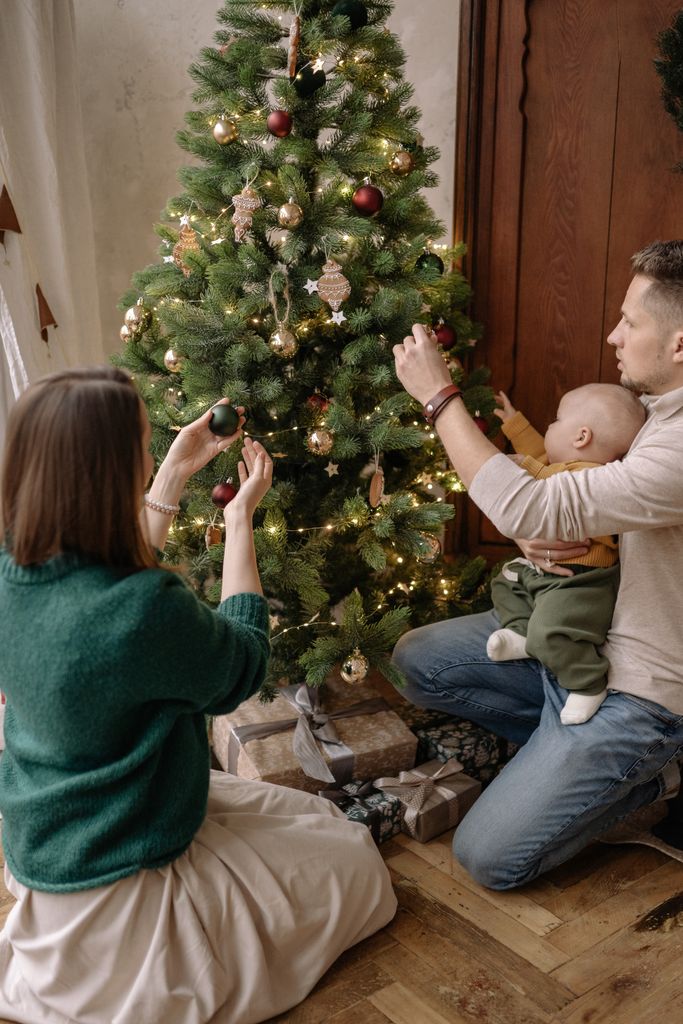 Family joyfully decorating a Christmas tree with lights and ornaments. Cozy holiday atmosphere.