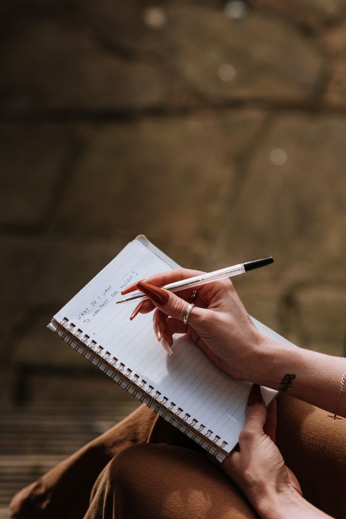From above of crop anonymous female writing her October bucket list on blurred background