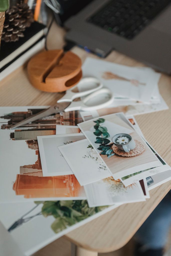 From above of various images scattered on wooden table near netbook for remote work from home make a vision board