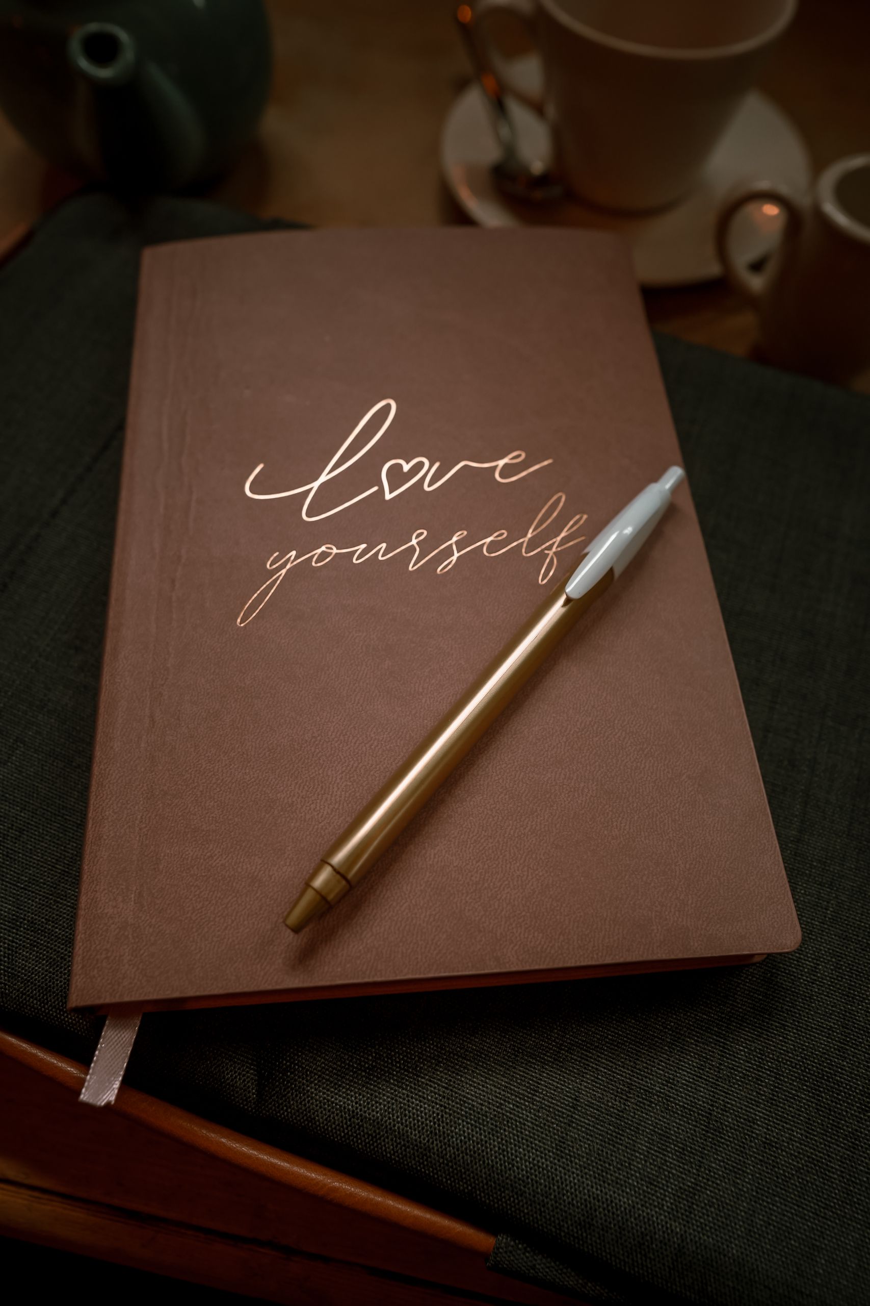 Inspirational notepad with 'love yourself' message in a cozy cafe setting, Manchester.