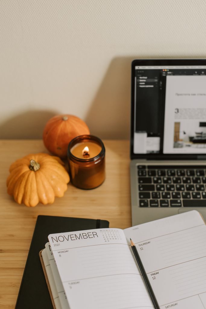 NOVEMBER BUCKET LIST ideas IN AN Inviting home office setup with a candle, pumpkins, and planner.
