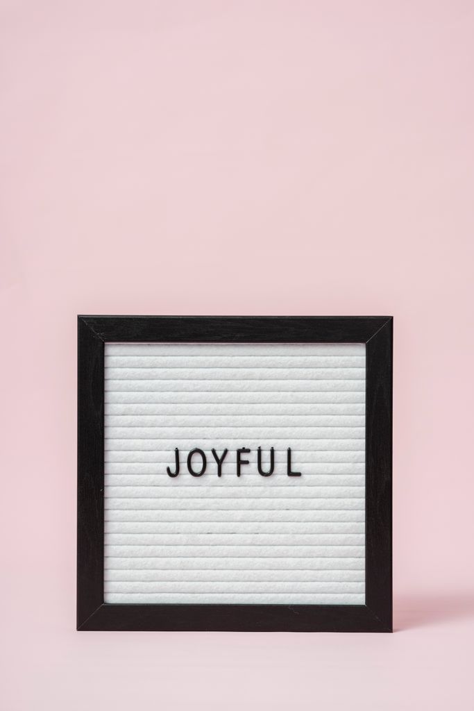 Letter board with 'Joyful' text on a minimalist pink background, perfect for positive messages. word of the year ideas