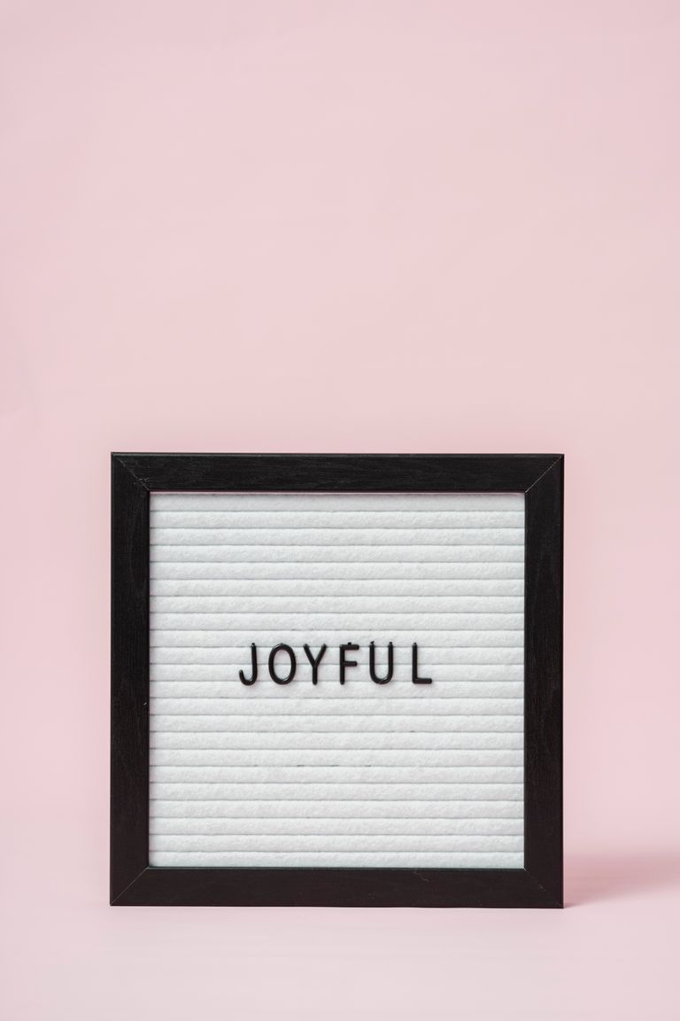 Letter board with 'Joyful' text on a minimalist pink background, perfect for positive messages.