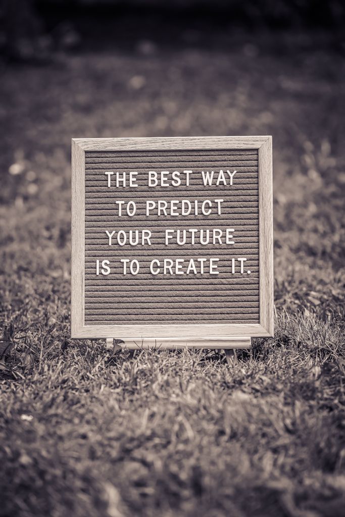 Letter board with motivational quote on grass background in black and white.