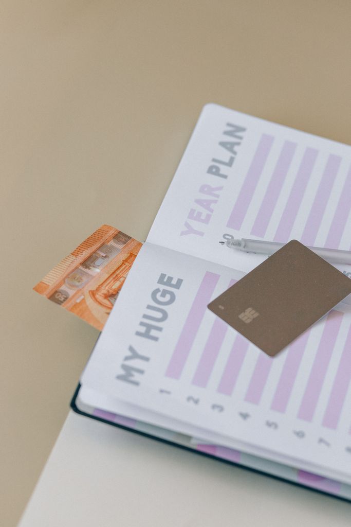 Open planner with credit card and banknote on table, perfect for financial planning concepts.how to plan your life