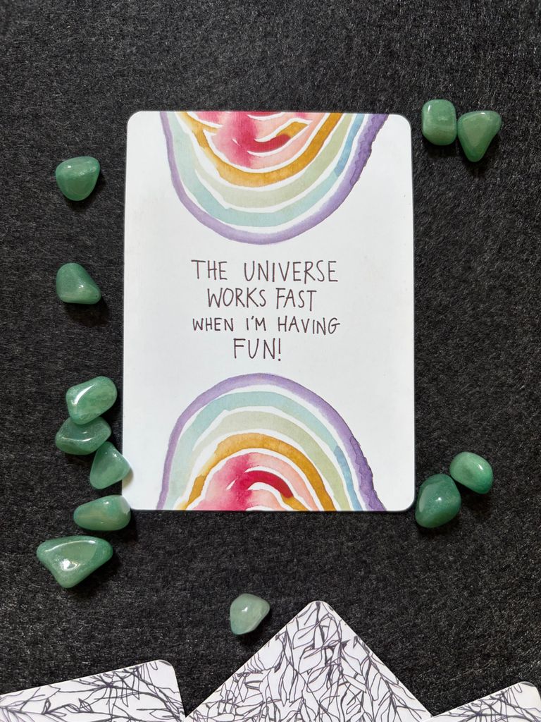 Rainbow-themed motivational card surrounded by green crystals for positive energy. best manifestation techniques