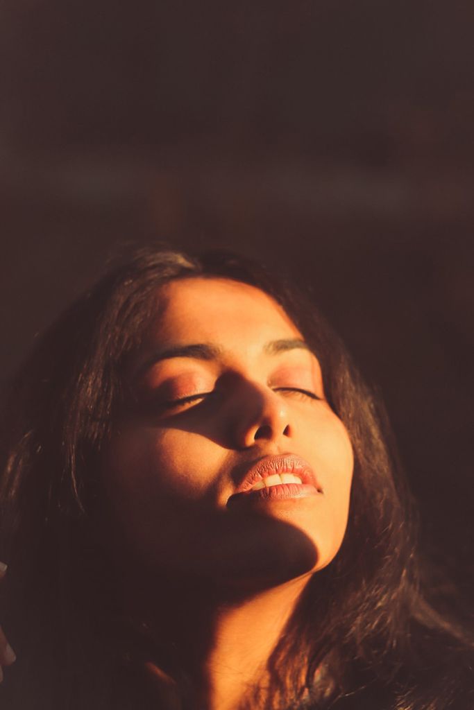 Serene close-up portrait of a woman enjoying warm sunlight with closed eyes.