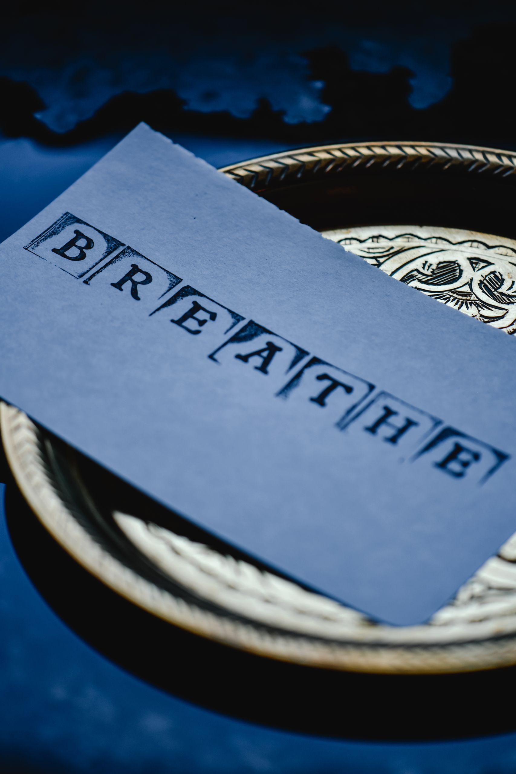 Serene still life featuring 'Breathe' card on a decorative plate, encouraging mindfulness.