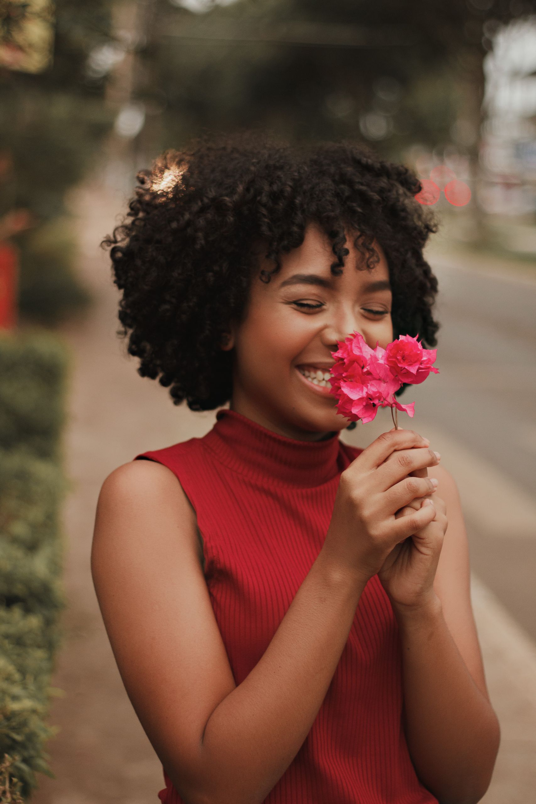Smiling woman enjoying bougainvillea flowers outdoors, showcasing natural beauty and happiness.