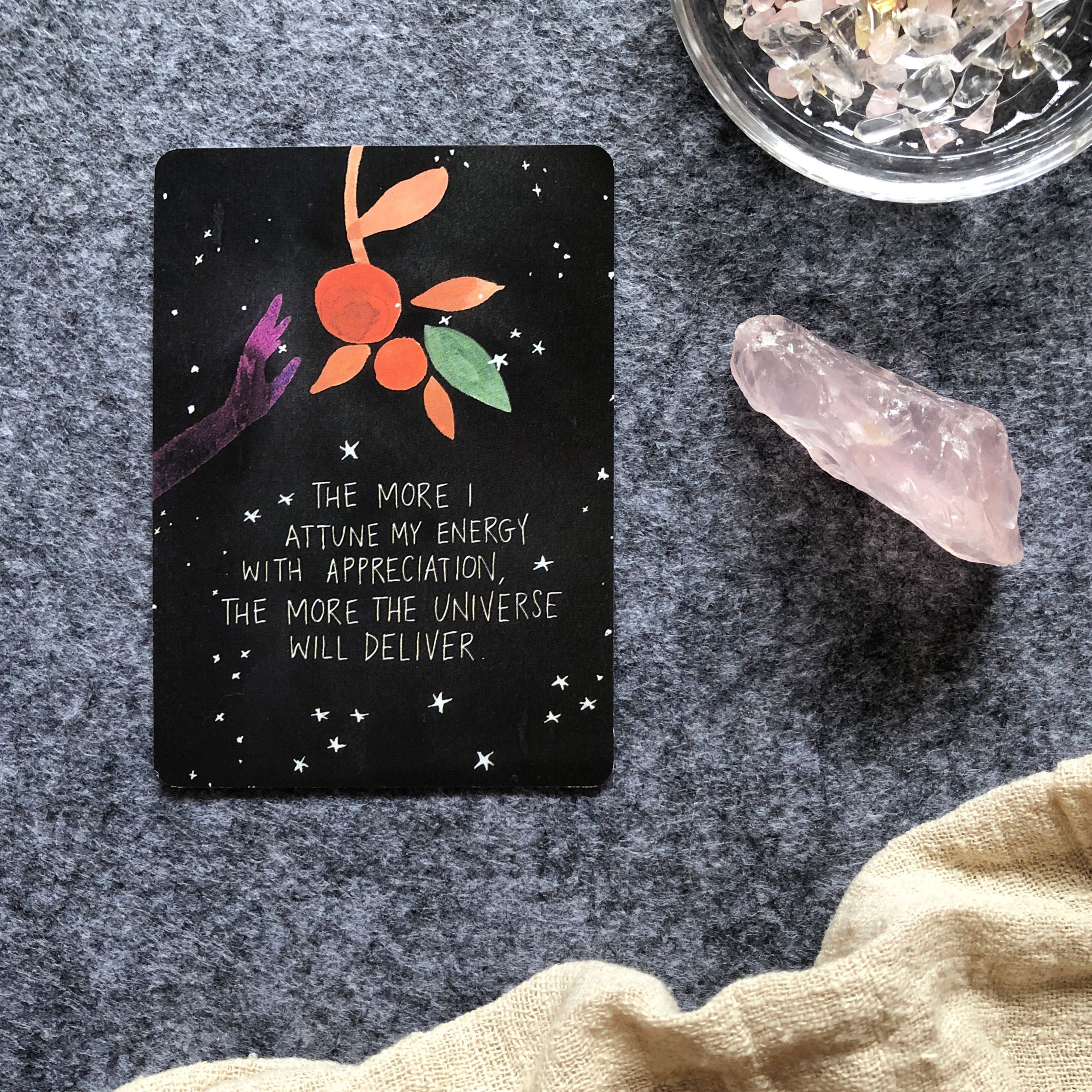 Tarot card with crystals on a textured background, featuring an inspirational quote about energy and appreciation.