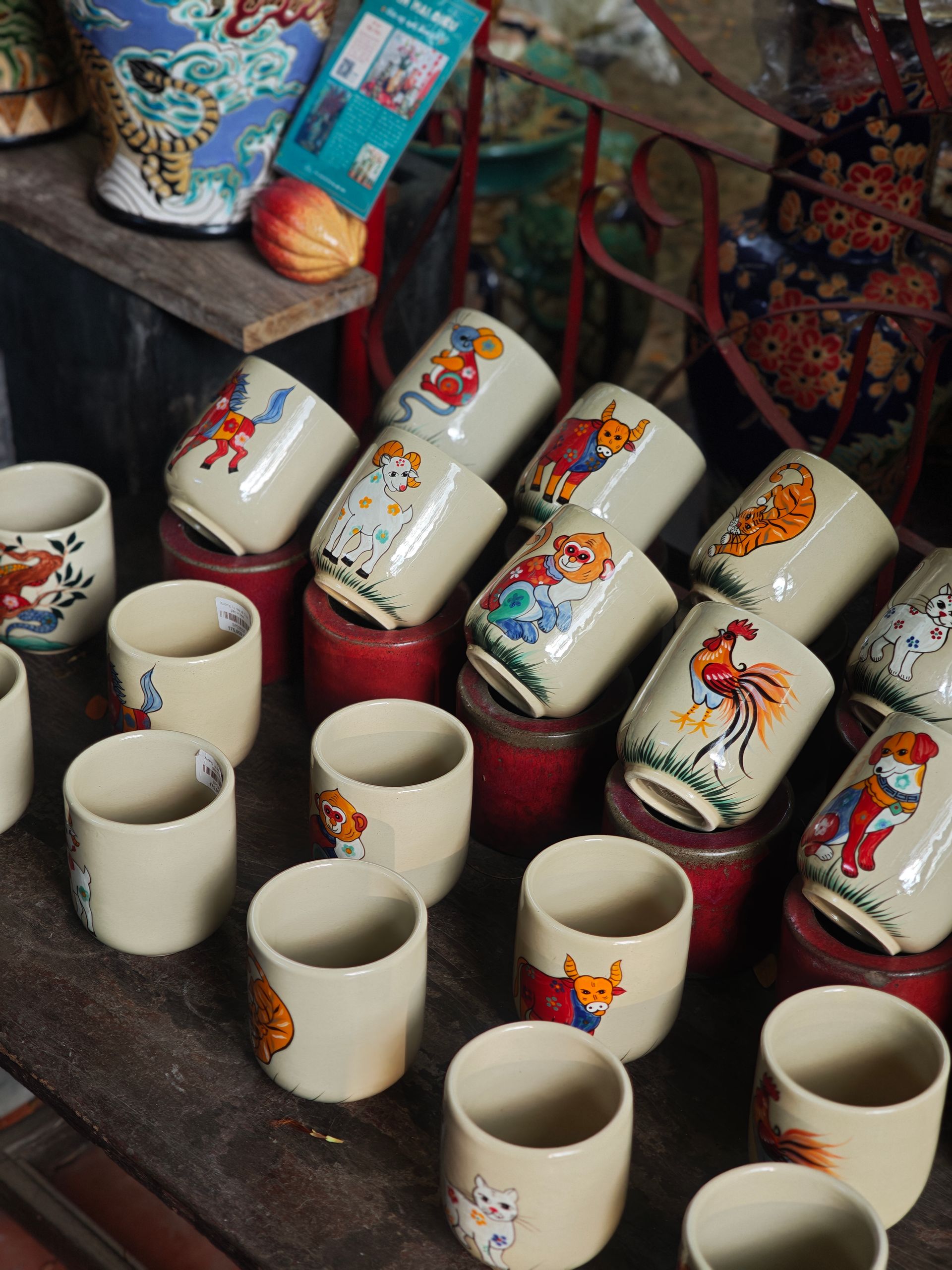 Vibrant hand-painted ceramic cups featuring animal designs on display in a market stall.