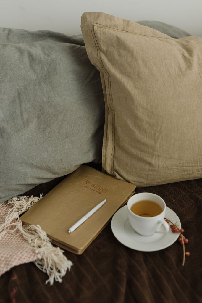 Warm and inviting setting with tea, notebook, and throw pillows, perfect for relaxation.new week journal prompts
